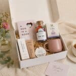 A Hug In A Box Gift Hamper open near a vase of flowers