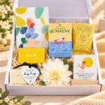 A Little Box of Sunshine Gift Hamper Australia featuring affirmation cards, inspirational journal, shower steamer, chocolate treat and hug keepsake in an open white gift box.