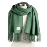 Green scarf draped over a mannequin with fringed ends on both sides, showing length and texture.