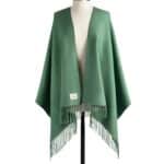 Green fringed poncho draped on a mannequin.
