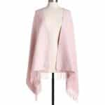 Light pink shawl with long fringe laid over a dress form, draped to show its open front and soft texture.
