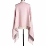 Light pink poncho/shawl with fringe ends draped over a dress form, showing a soft, oversized wrap.