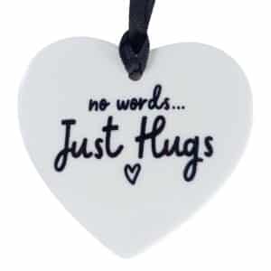 White heart-shaped ornament reading 'no words... Just Hugs' with a small heart, hanging from a black ribbon.