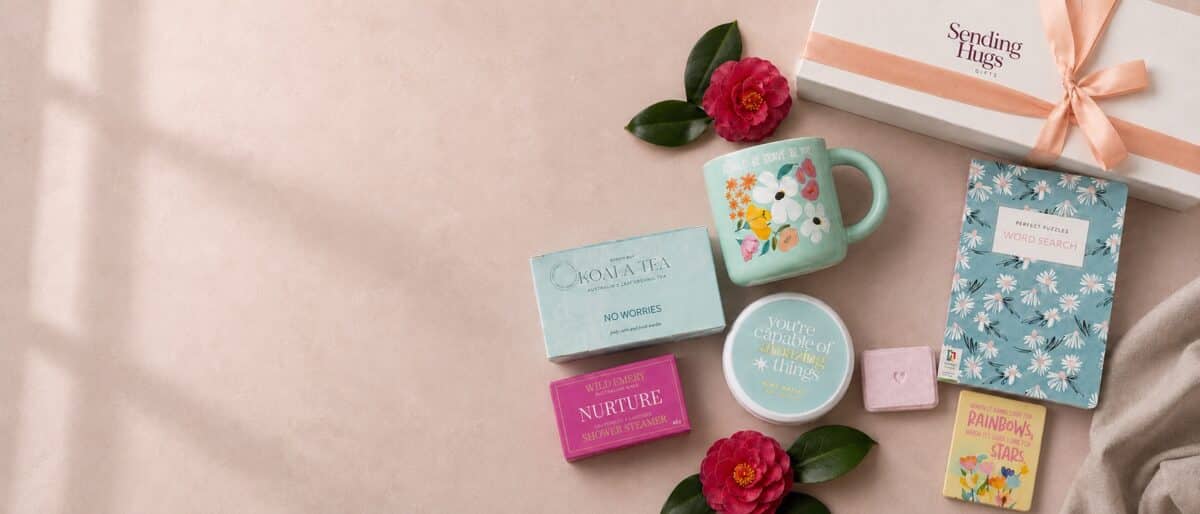 Colourful Sending Hugs gift hamper products arranged on a soft blush background for delivery across Victoria.