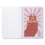 Open notebook; right page features a pink framed poster with a red glittery boot and the words 'FUN IS GOOD'.
