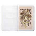 Open notebook with a peach quote card on the right page displaying: 'Take the world's wide gift of joy and beauty.'