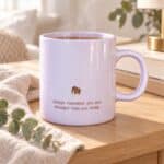 Stronger Than You Think Ceramic Mug with gold elephant styled with tea, eucalyptus and linen in natural light