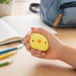 Hand squeezing the yellow Squishy Jelly Chick sensory fidget toy