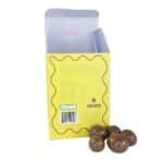 Back of packaging for the Milk Chocolate Macadamias 100g with a couple of chocolates at the base