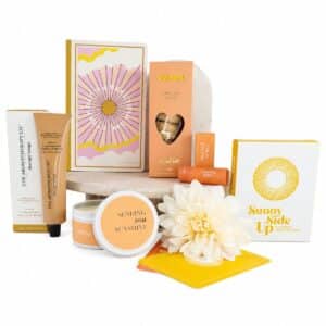 Sending Sunshine Self-Care Gift Hamper featuring sunshine candle, notebook, self-care cards, hand cream, lip balm and vanilla biscuits.