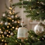 Stoneware Mini Guardian Angel Bell Hanging on a branch of a Christmas Tree
