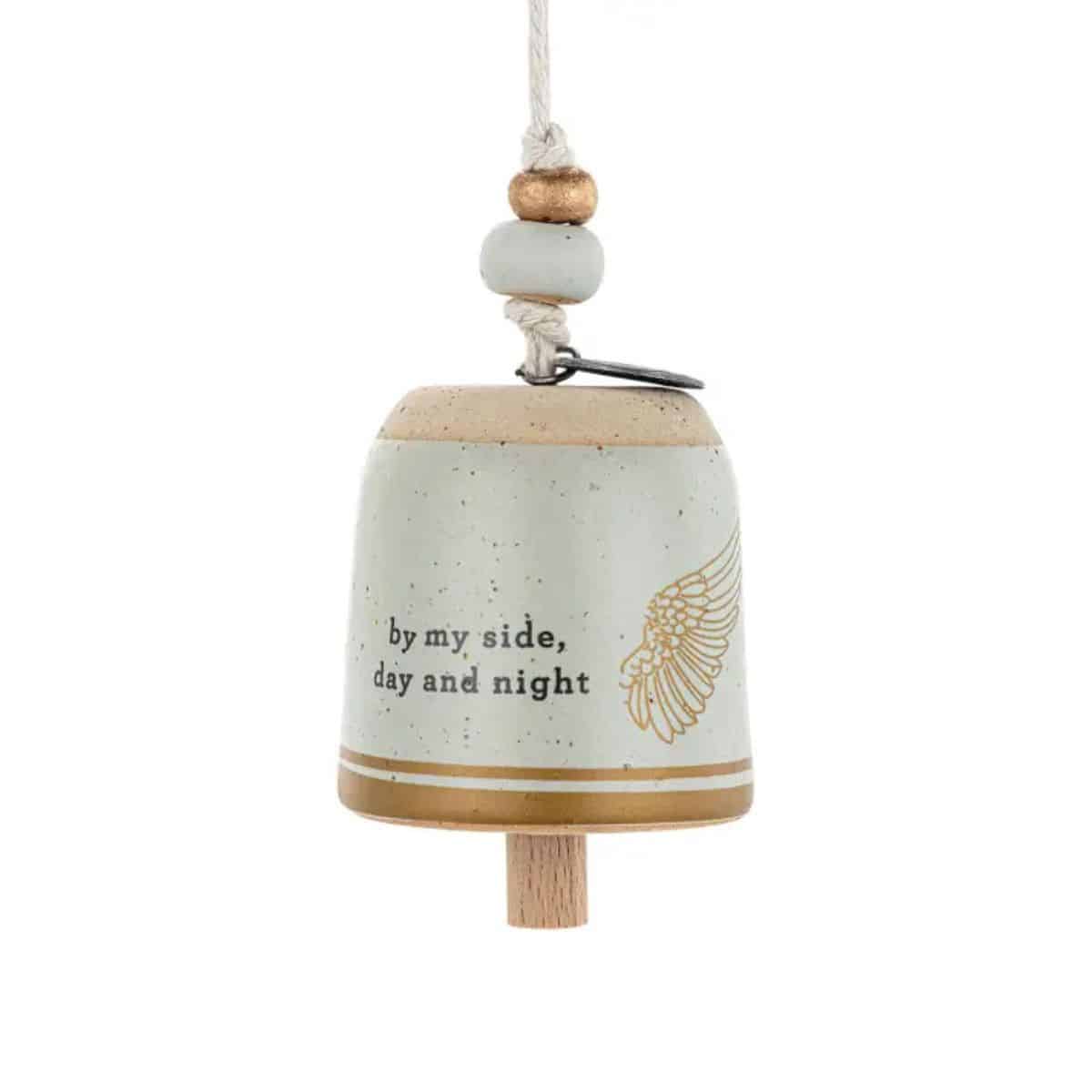 Showing the Stoneware Mini Guardian Angel Bell with gold angel wing design, comforting 'by my side, day and night' message and decorative beaded cotton hanging cord out of the included gift box