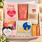 Thinking of you gift hamper displayed in an open white gift box with Warm Hugs socks, inspirational book, relaxation essentials and thoughtful self-care gifts.